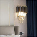 Modern wall-mounted light fixture on a neutral wall with a bed in the foreground.