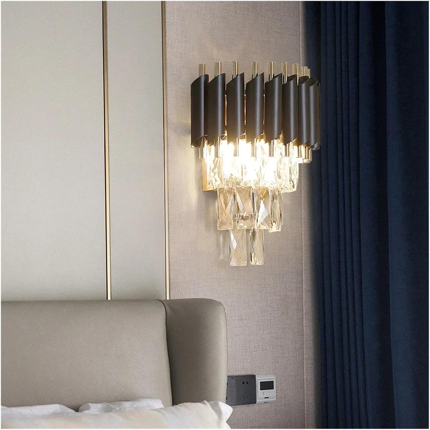 Modern wall-mounted light fixture on a neutral wall with a bed in the foreground.